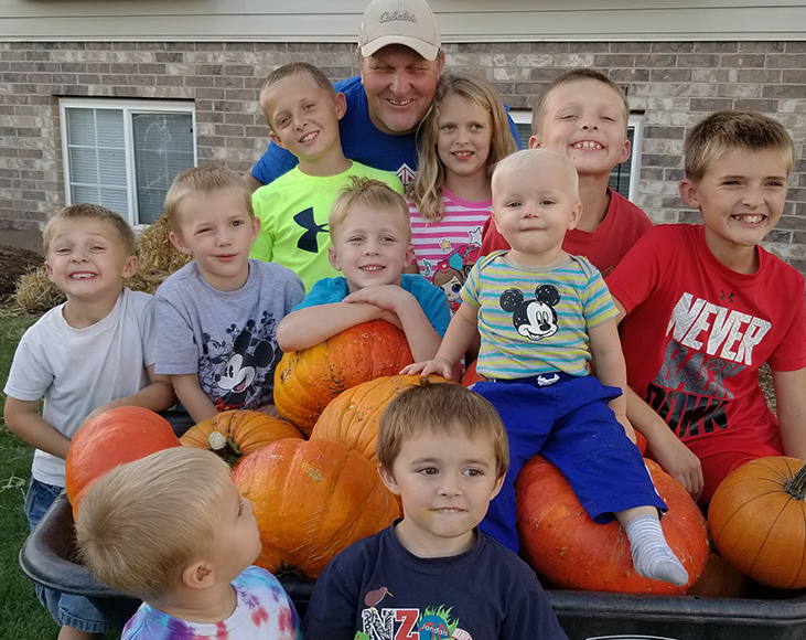 Grandkids sitting on a wagon with pumpkins - Gardening with kids lessons - The Grandkid Connection