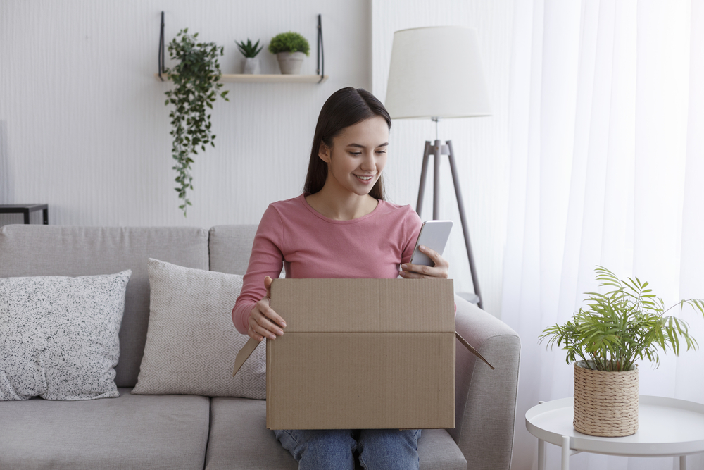 Girl sitting on couch holding a box while talking on video chat - Long-distance teenage grandchildren - The Grandkid Connection