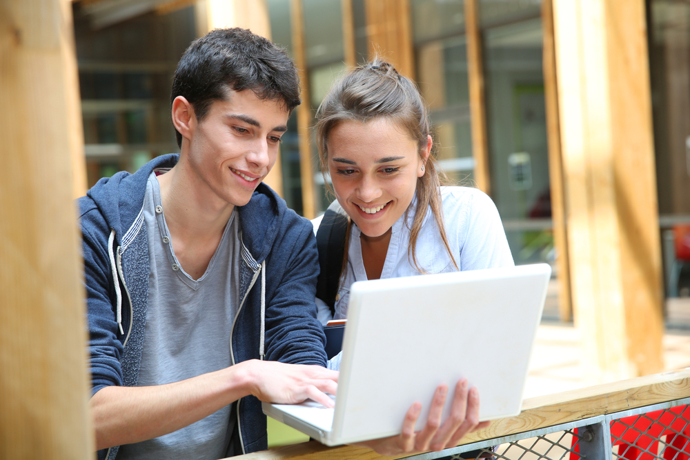 Two teenagers working on a laptop - The Grandkid Connection